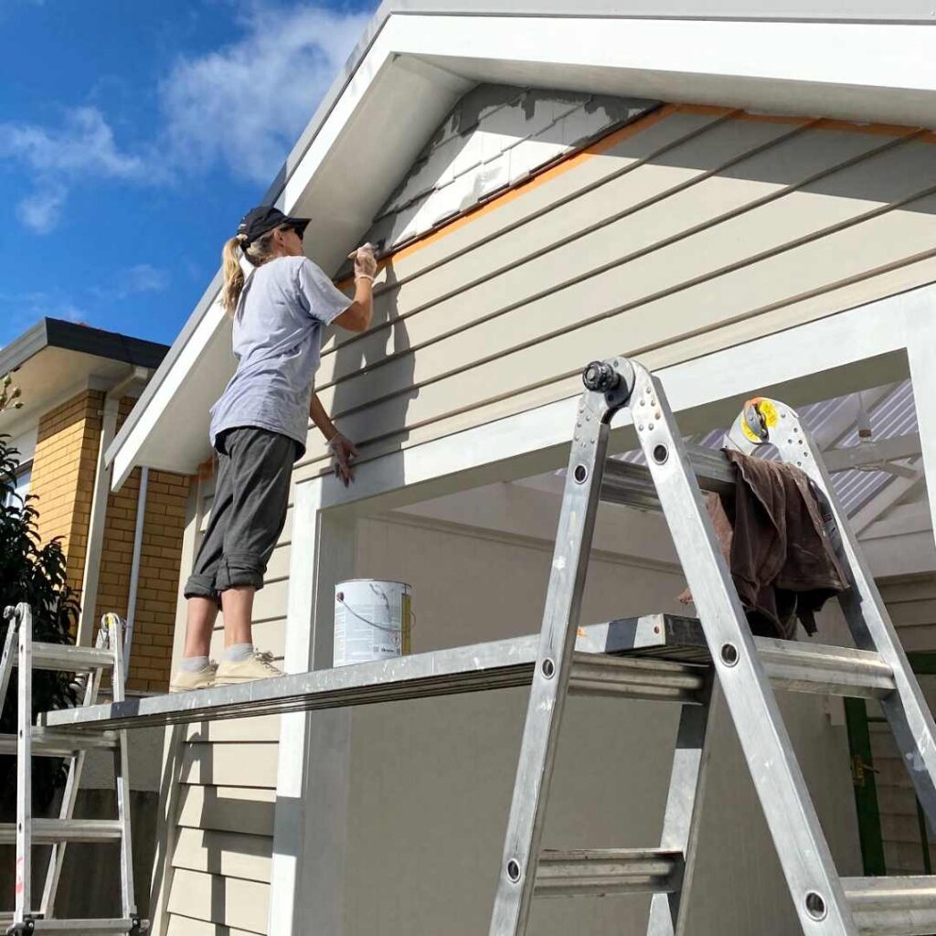 Newly painted weatherboards and cedar shingles matching villa colours on transformed outdoor space.